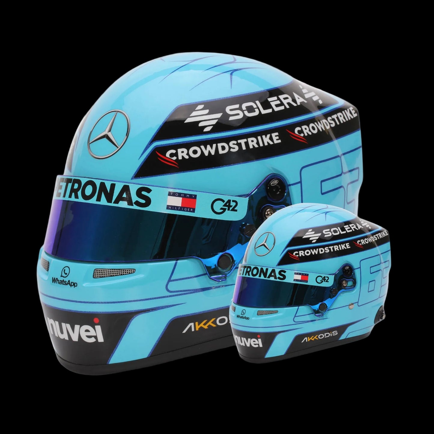 A mini replica helmet of George Russell, Mercedes F1 driver, in a 1:2 scale, featuring a light blue color with black and white accents, along with sponsor logos such as 'Astronas' and 'Crowdstrike'.